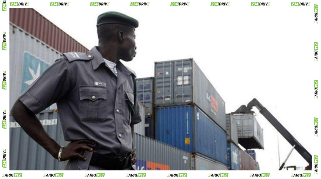 A Nigerian customs officer overseeing imported containers at a shipping terminal amid new vehicle import regulations.