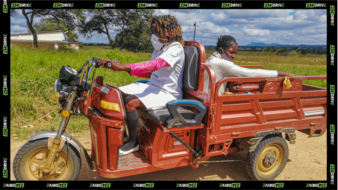 A nurse drives an electric tricycle across rough rural roads, carrying a mother and child to essential care.