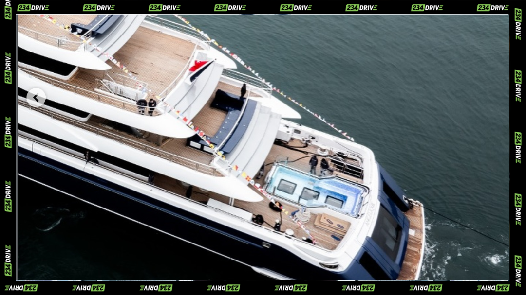 Crew members ready the aft deck, revealing the yacht’s layered terraces and pool cascading down toward the open sea.