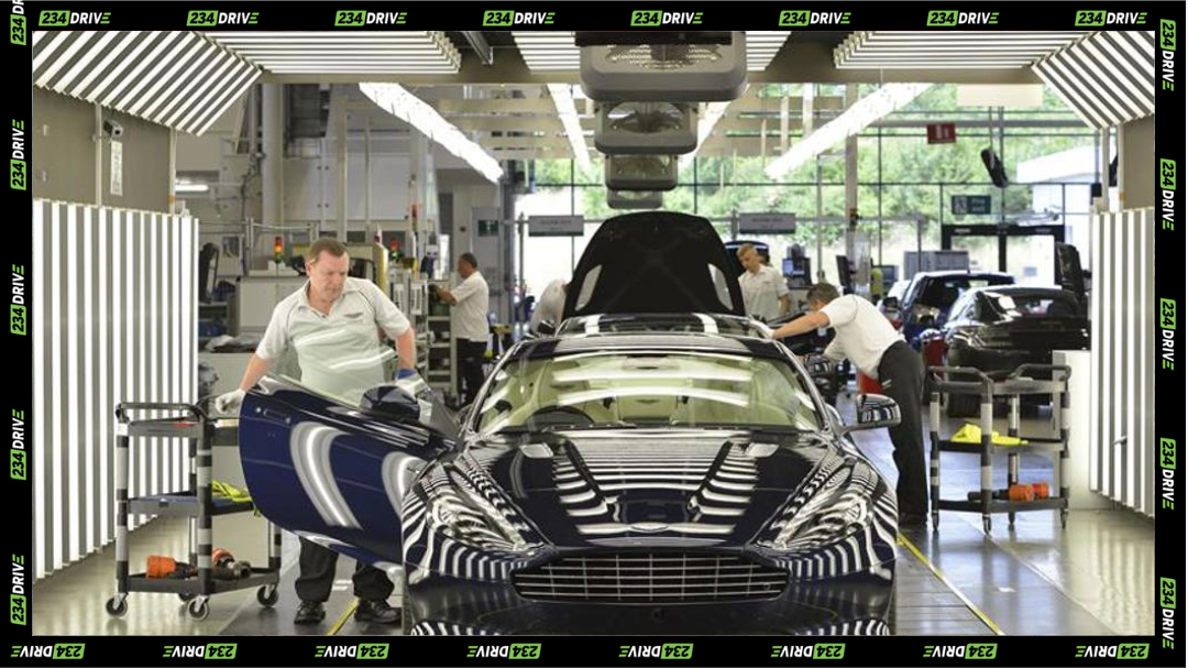 Technicians assemble an Aston Martin sports car inside a modern factory floor.