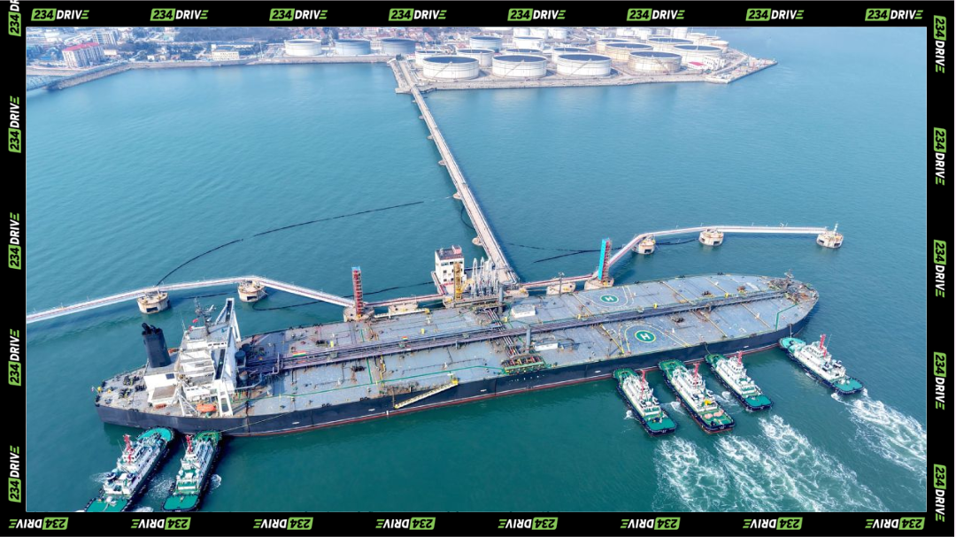 Massive oil tanker offloads crude at a coastal terminal in China while tugboats assist with docking and cargo transfer. As China's economy withstand global oil pressure