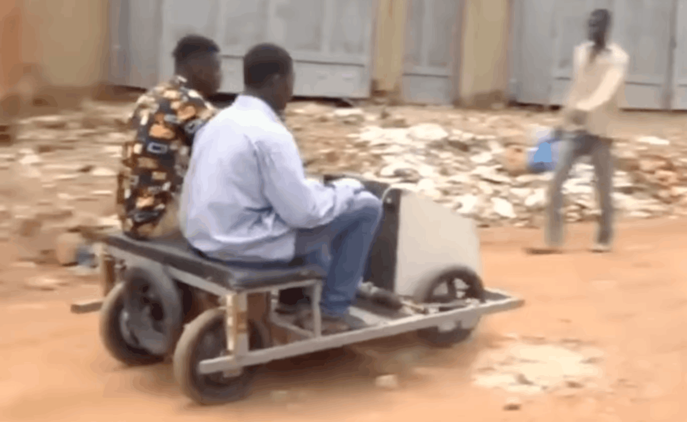 Ude’s handmade electric car carries two passengers during a test run in Burkina Faso.