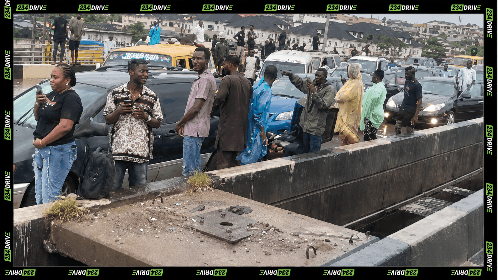 A white car and yellow bus move through floodwater on the Ojota-Maryland Bridge as pedestrians watch from the roadside in Lagos.