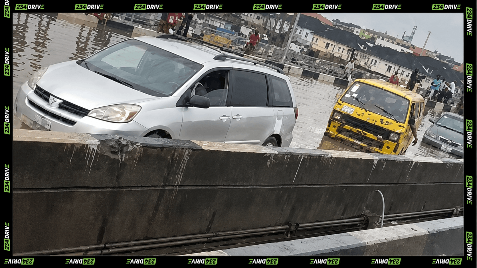 Lagos commuters stand beside cars and buses caught in floodwater on the Ojota-Maryland Bridge as heavy rain disrupts movement in Lagos.