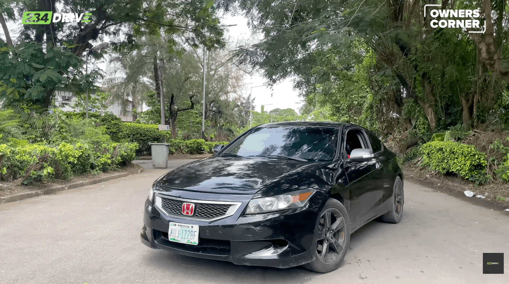 Bugsy’s black Honda Accord Coupe shows its sporty front design and modified wheels while parked on a quiet, tree-lined Lagos road.