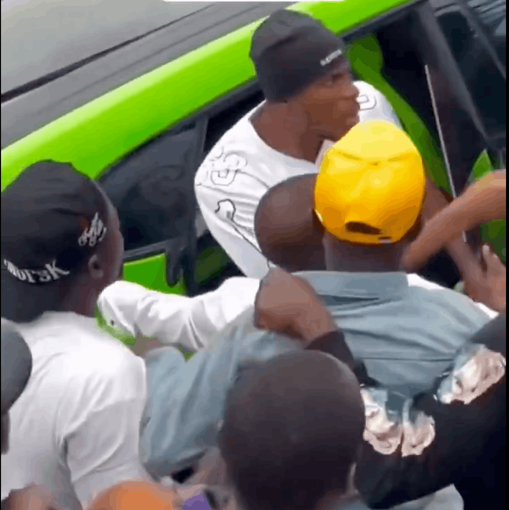 Crowd of young men surrounding a green car in Lagos reflects aggressive street begging and pressure on motorists to hand over money.