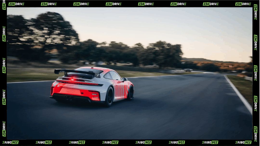 The Porsche 911 Challenge accelerates around a race circuit, showing its rear wing, wide body, racing slicks and track-only aerodynamic setup.