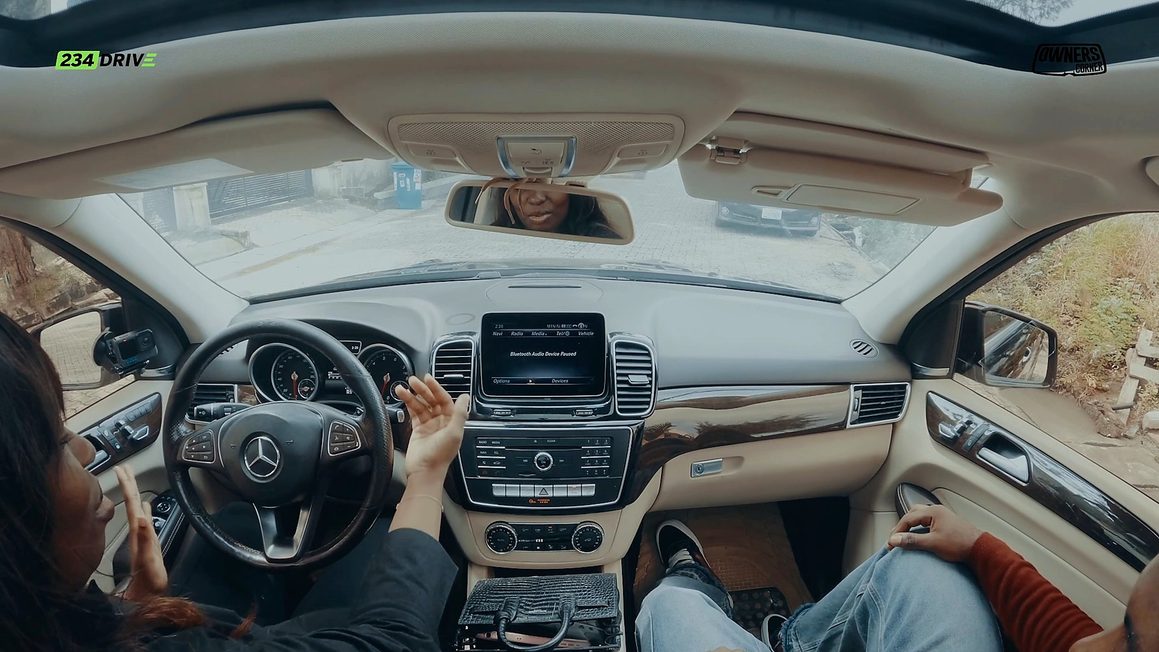 Tola Badmus talking and gesturing in the driver’s seat of her GLE 350 with the panoramic roof overhead