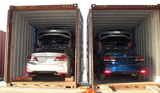 Two open shipping containers, each loaded with two Honda Civics, one stacked above the other on a car rack