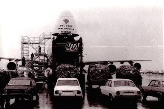Archival photo of a UTA Cargo aircraft with its nose open on a tarmac, offloading early imported Peugeot vehicles for the Nigerian market