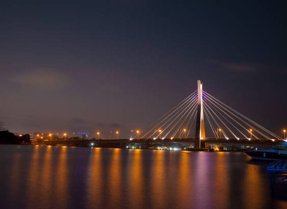 The illuminated Lekki-Ikoyi Link Bridge stretching across calm dark waters at night in Lagos Nigeria
