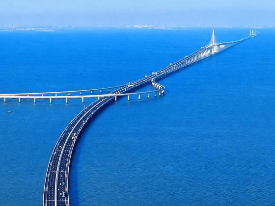 Aerial view of a long coastal bridge stretching across the blue sea.