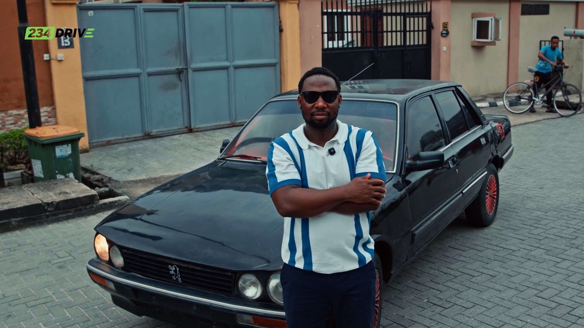 Ameen stands with arms crossed in front of his black Peugeot 505 outside a gated home